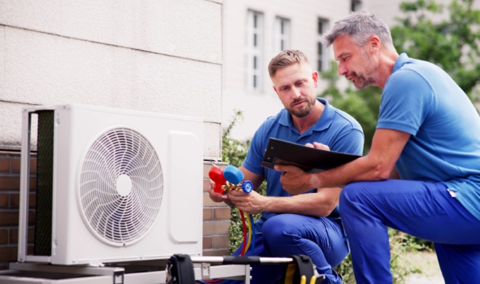 HVAC technicians reviewing an outdoor air conditioning unit in Mesa, AZ