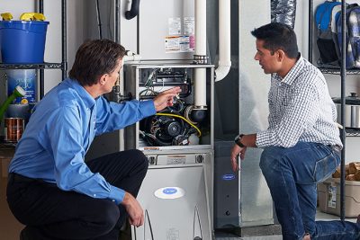 HVAC technician explaining furnace repair and maintenance to a homeowner in Mesa, AZ